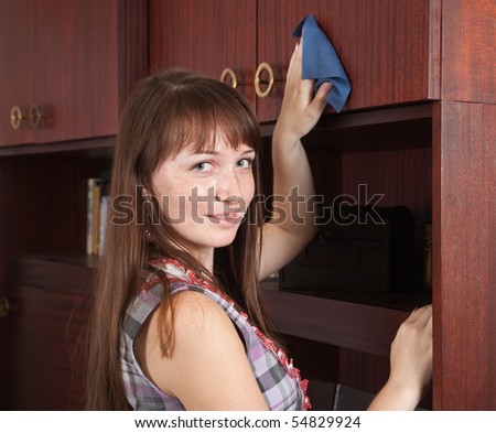 Brunette young girl cleans a furniture indoor