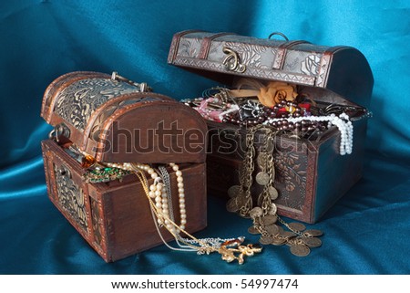Two wooden treasure chests with valuables on blue textile
