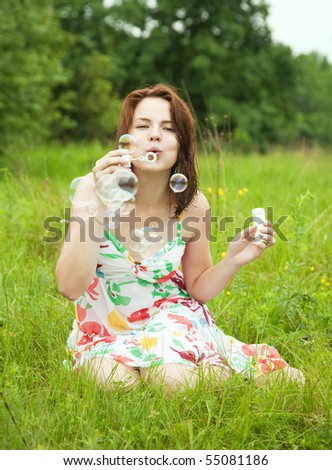 girl making soap bubbles on meadow grass