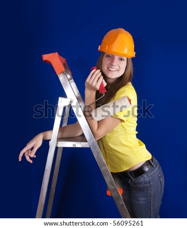 Girl in hard hat with paint rollers on stepladder