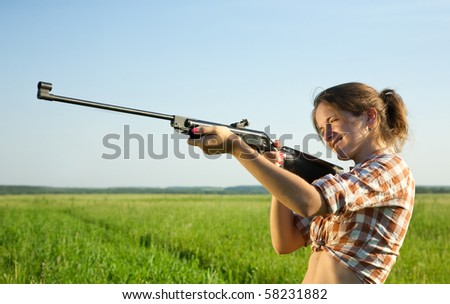 girl  aiming a pneumatic air against summer field