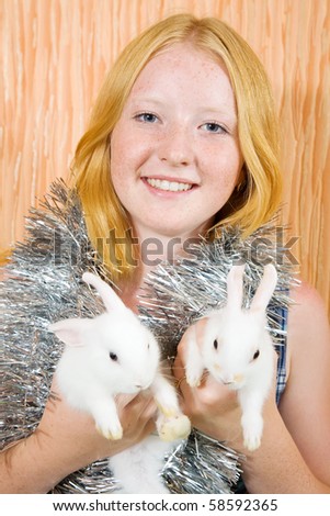Teen  girl with two pet rabbits sitting in home