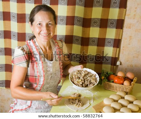 elderly woman cooking meat pasty at kitchen