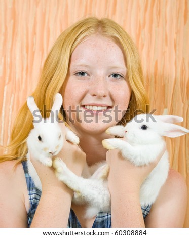 Teen  girl with two pet rabbits smiling indoor
