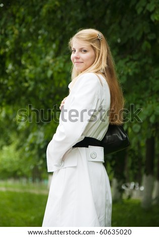 Pretty blonde girl in white cloak standing outdoors