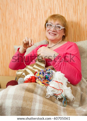 senior woman knitting with knitting-needle on sofa at home