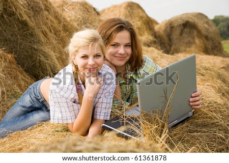 country girls with laptop on  hay at field