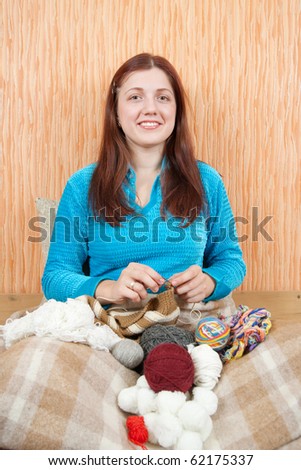 young woman knitting with knitting-pin at home