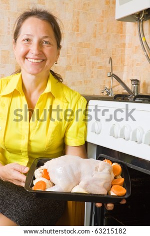 Mature woman roasting stuffed chicken on  pan in oven. One of the stages of preparation of  stuffed stuffed.  See series