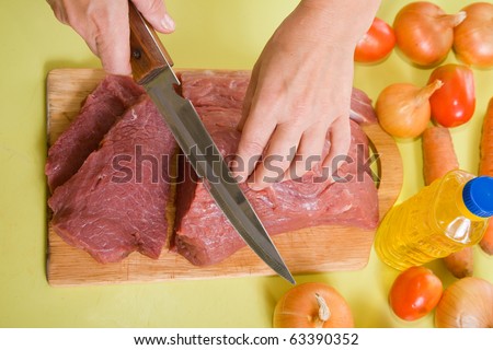 Closeup of cook hands cutting beef on cutting board. One of the stages of preparation of the stuffed beef.  See series