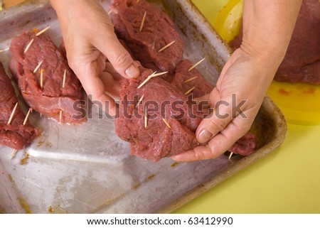 Closeup of cook hands puts stuffed beef to cook griddle. One of the stages of preparation of the stuffed beef.  See series