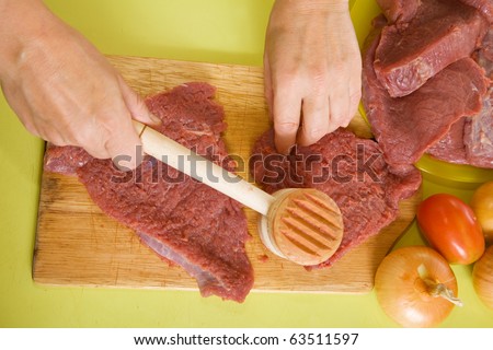 Closeup of cook hands making tenderized steak with meat hammer. One of the stages of preparation of the stuffed beef.  See series