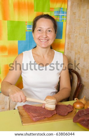 Mature woman making meat tenderizer with meat hammer. One of the stages of preparation of the stuffed beef.  See series