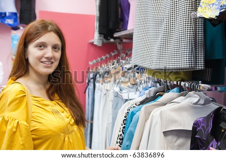 young woman chooses clothes at clothes shop