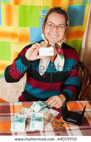 Happy senior woman with  credit card  and money at her home