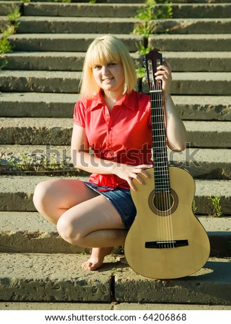 Blonde girl with guitar on steps of stair