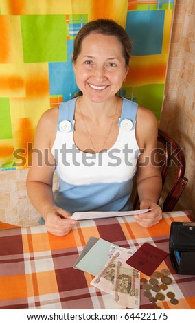 Happy mature woman with money at her home