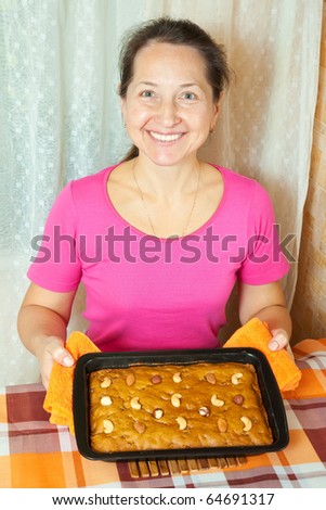 Mature woman  with fresh  honey cake. One of the stages of cooking of  honey cake.  See series