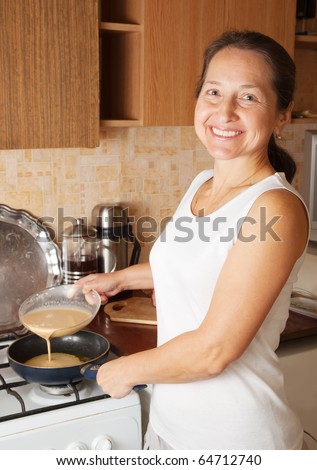Mature woman doing an omelet at kitchen. One of the stages of cooking  omelet.  See series