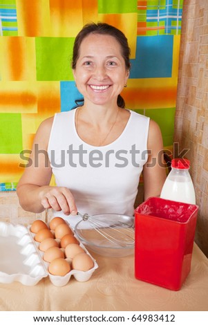 Mature woman with food products for omelette in her kitchen. One of the stages of cooking  omelet.  See series