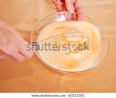 Cook hands beating up  eggs and milk in dish. One of the stages of cooking  omelet.  See series