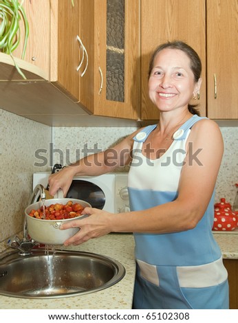 Woman washing strawberries in the kitchen sink