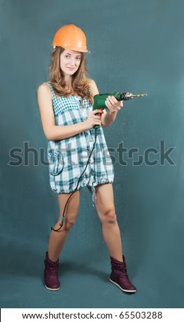 Female construction worker in a hard hat with drill over grey background