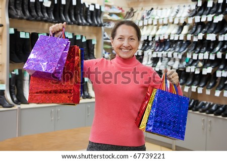 Happy mature woman with shopping bags at  shoes shop