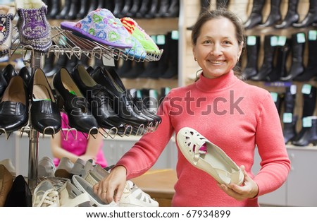 Mature woman chooses shoes at shoes shop