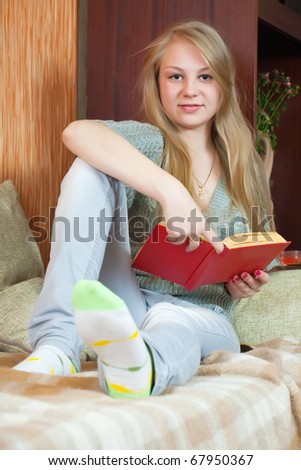 Long-haired female student reading book at home
