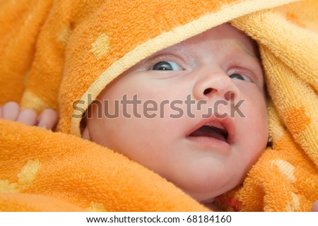 Newborn baby wrapped in orange warm blanket
