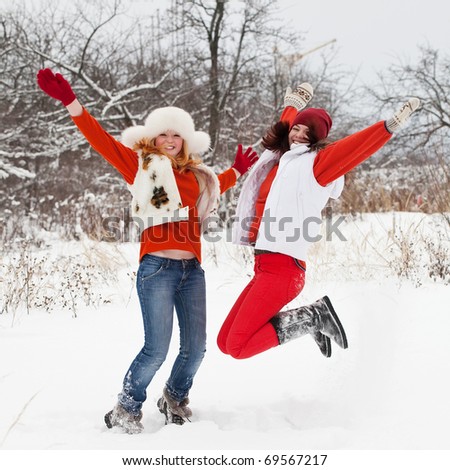 Two happy girls is jumping at  winter park
