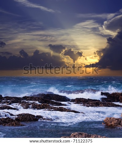 Sea wave breaking against coast  rock in sunset time