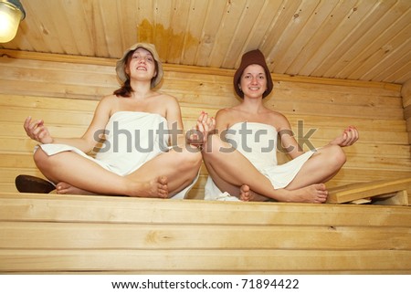 Beautiful young women practicing yoga  at sauna