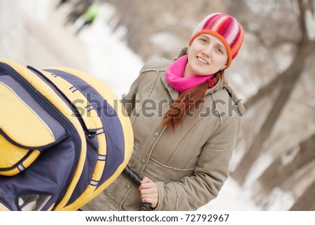 mother with her baby in pram walking at winter park