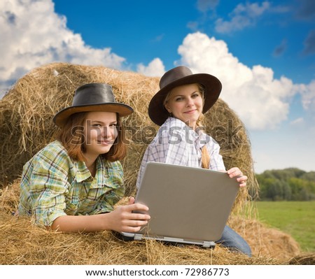 country girls in cowboy hat with laptop on  hay at field