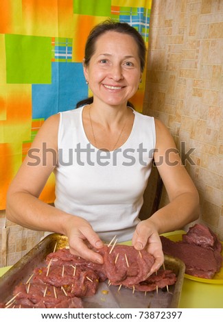 Mature woman puts stuffed beef to cook griddle. One of the stages of preparation of the stuffed beef.  See series