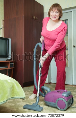Woman cleaning with vacuum cleaner in living room