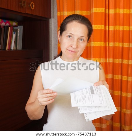 Sad mature woman with utility bills  at her home