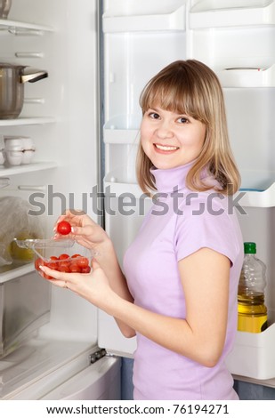 Young woman taking  Cherry-tomatoes    from refrigerator  at home