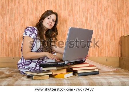 young girl sitting on the sofa with laptop and books