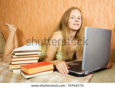 Sexy student lying on sofa in livingroom with laptop and books