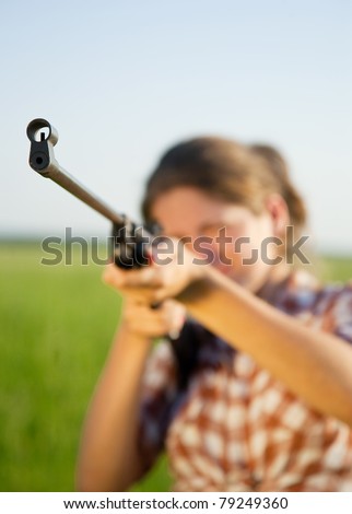 girl  aiming a pneumatic rifle against field. Focus on  barrel only