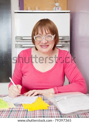 Sad mature woman with utility bills  at her home