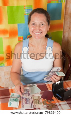 Happy mature woman with money at her home