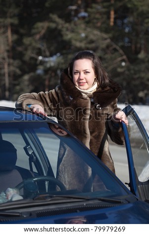 Smiling woman get in the car and looking at camera
