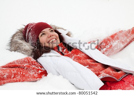 Happy girl lying down on the snow in winter