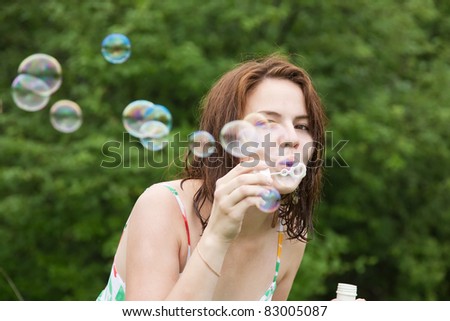 Pretty girl making soap bubbles against trees