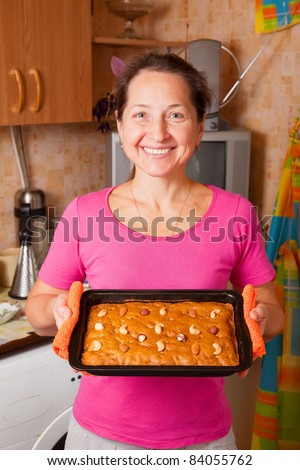 Mature woman  with fresh  honey cake. One of the stages of cooking of  honey cake.  See series