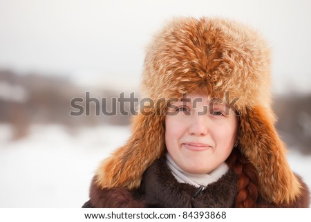 Portrait of smiling girl in fur cap at wintry park